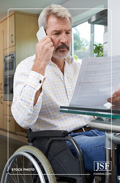 Concerned disabled white man in a wheelchair on the phone while holding a document.